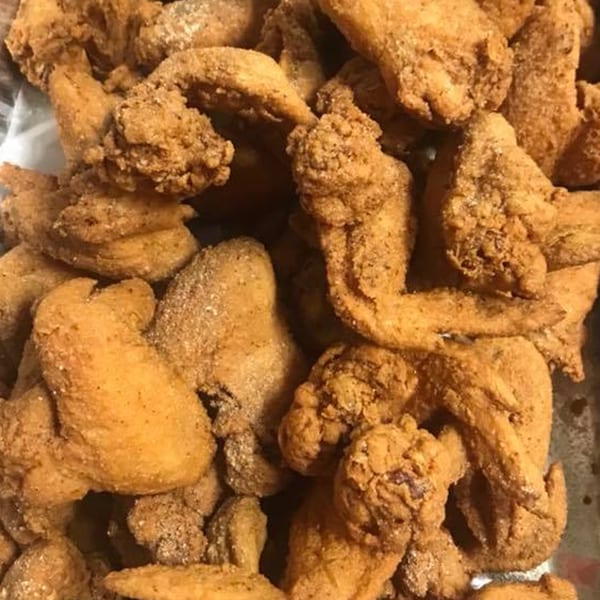 Close-up of a large pile of golden-brown, crispy fried chicken pieces from Eddy's Chicken and Waffles.